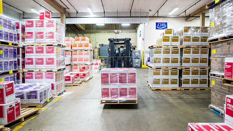 Forlklift operator moving a pallet of Cenex lubricants in a wareshouse.