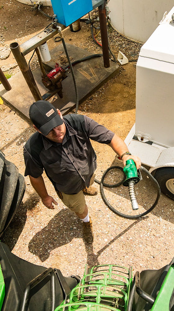 Man holding a fuel hose ready to put diesel fuel in a tractor.
